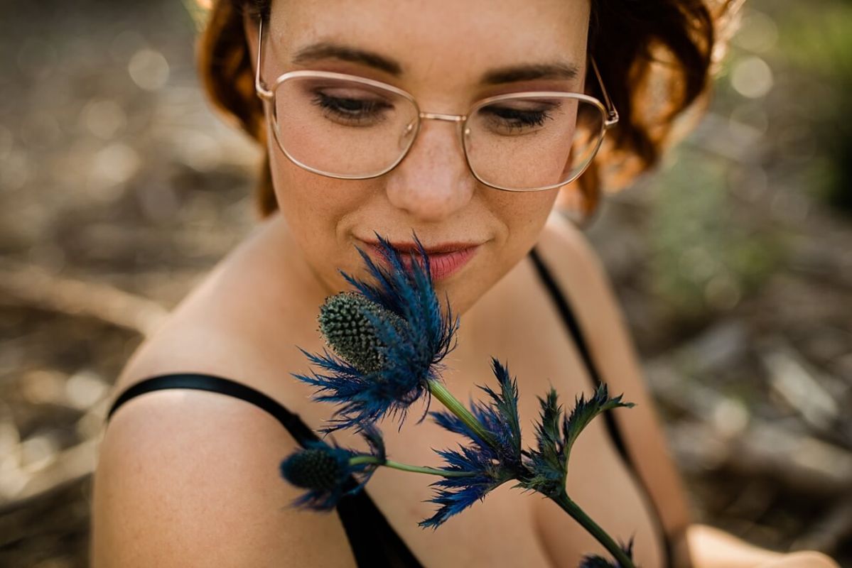 Mädchen mit Brille mit blauer Blume in sinnlicher Pose